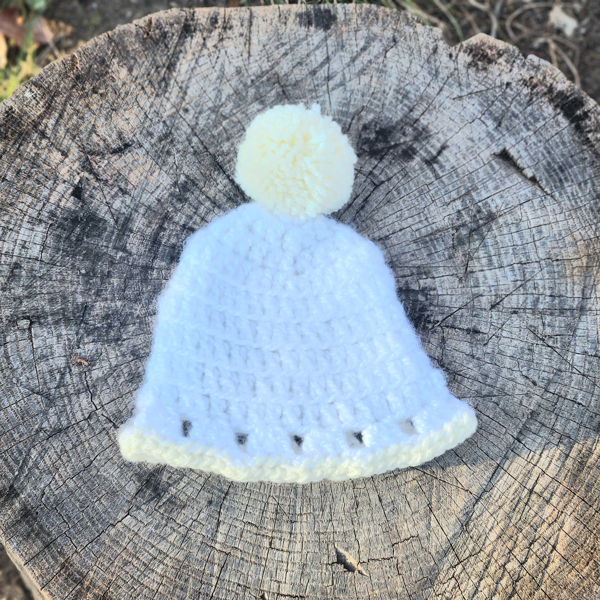 White crochet baby hat with pale yellow trim and pom pom 