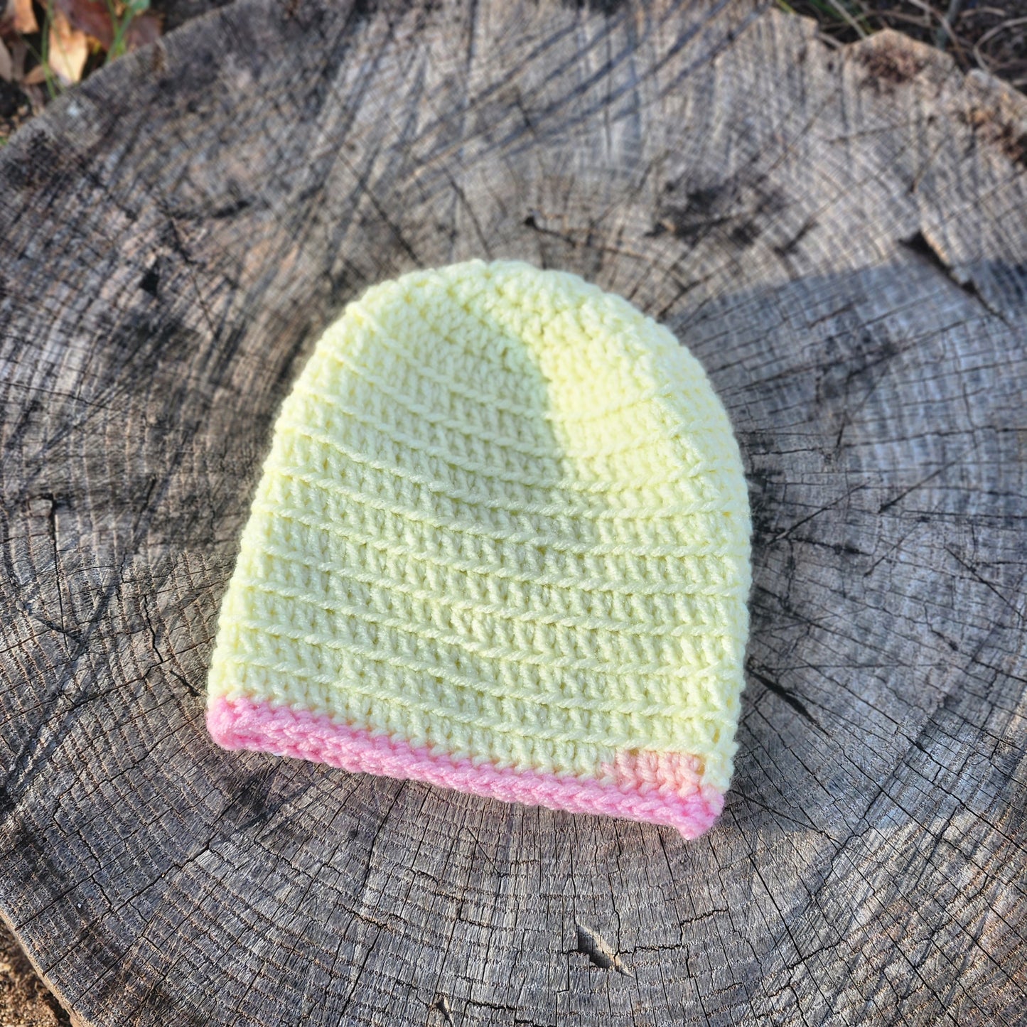 Pale yellow crochet baby hat with pink trim